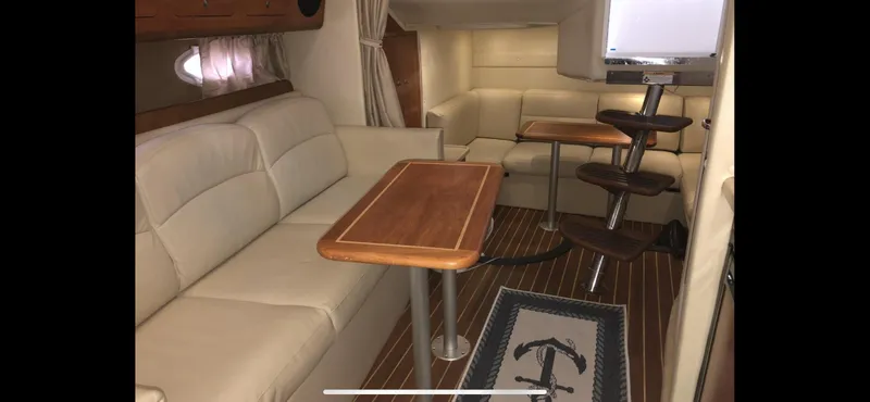 Slide: The Image of Interior of 2008 Rinker 350 Express Cruiser with beige seating and wooden tables. - 16