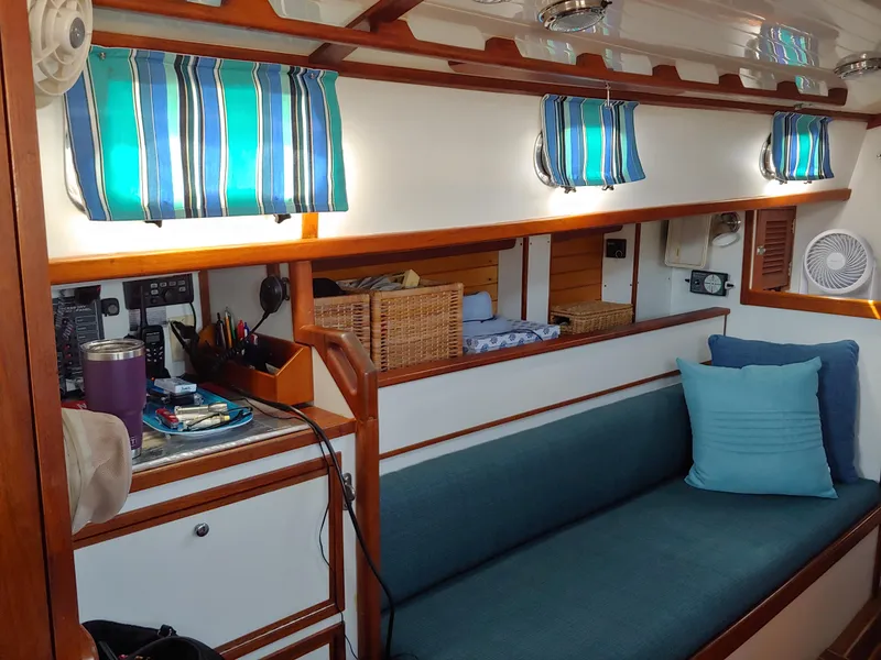 Slide: The Image of Interior of a 1994 Shannon 39 sailboat with blue-striped curtains and cozy seating. - 17