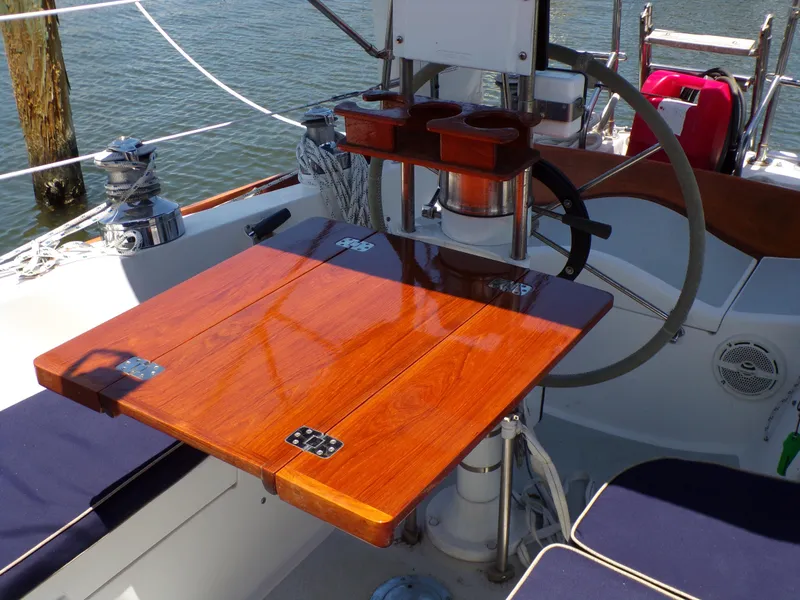 Slide: The Image of Polished wooden table on 1994 Shannon 39 sailboat deck, featuring steering wheel and cup holders. - 7