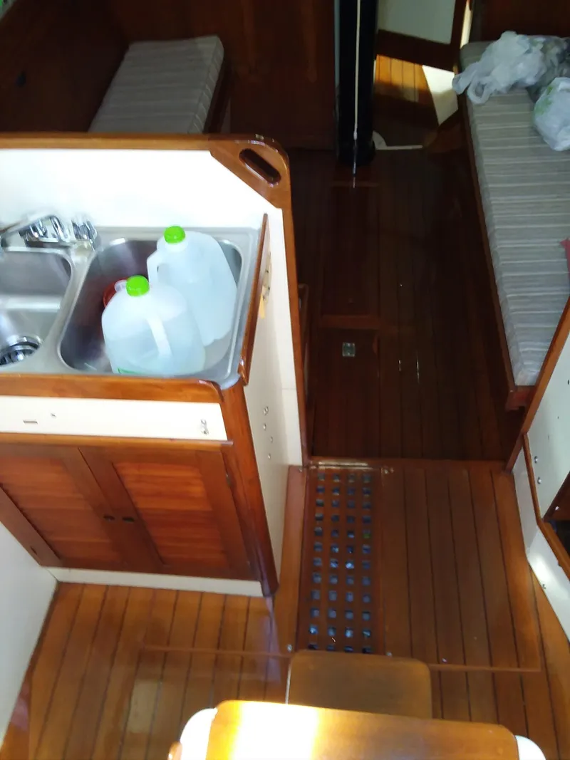 Slide: The Image of Interior of a 1972 Tartan 41 sailboat with wooden flooring and compact kitchen area. - 24