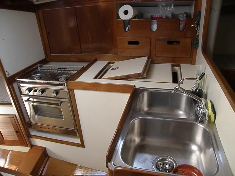 Slide: The Image of 1972 Tartan 41 yacht kitchen with stainless steel sink, stove, and wooden cabinetry. - 25