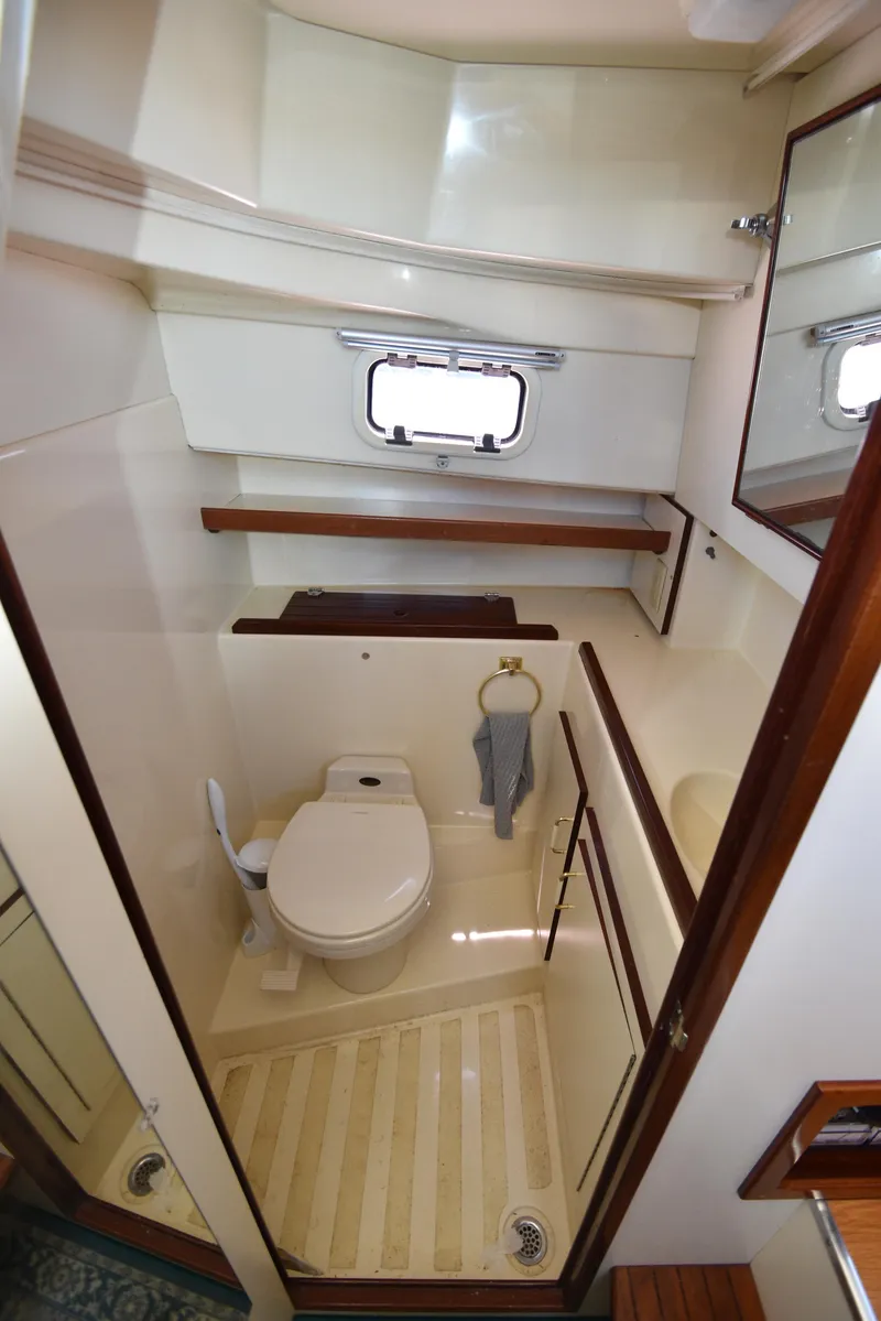 Slide: The Image of Compact bathroom in 2001 Camano 31 Trawler with toilet, sink, mirror, and porthole window. - 38