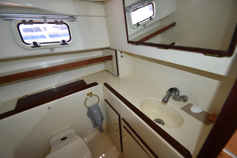 Slide: The Image of 2001 Camano 31 Trawler bathroom with sink, toilet, mirror, and porthole window. - 40
