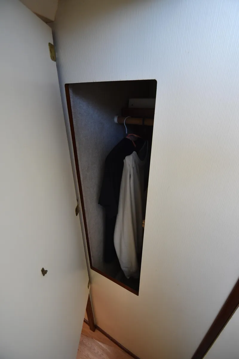 Slide: The Image of Small closet with hanging clothes inside a 2001 Camano 31 Trawler boat. - 42