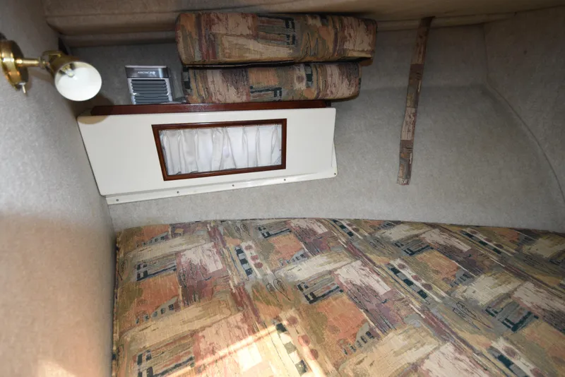 Slide: The Image of Interior cabin of a 2001 Camano 31 Trawler with patterned upholstery and a small window. - 46