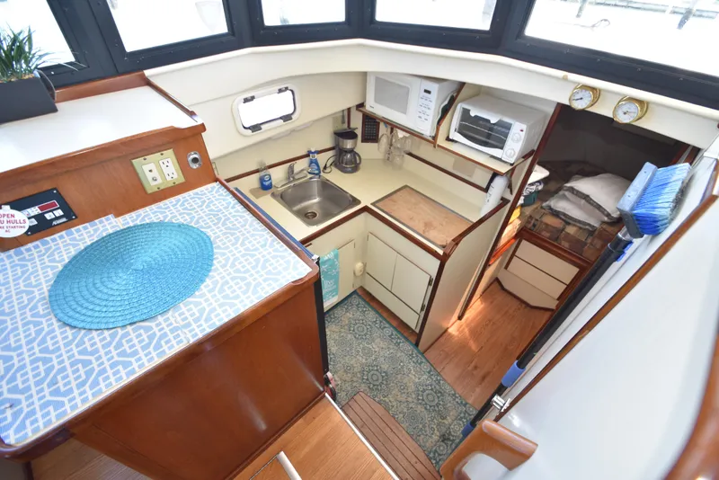 Slide: The Image of 2001 Camano 31 Trawler galley with sink, microwave, and cozy sleeping area. - 5
