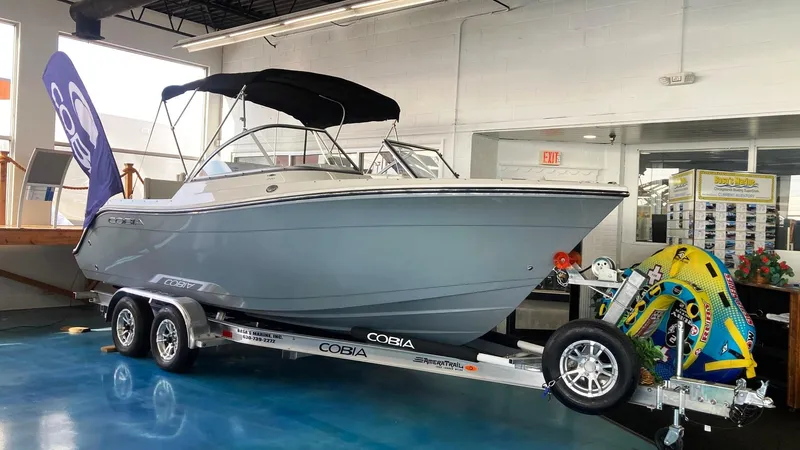 Slide: The Image of 2022 Cobia 220 Dual Console boat on trailer in showroom. - 0