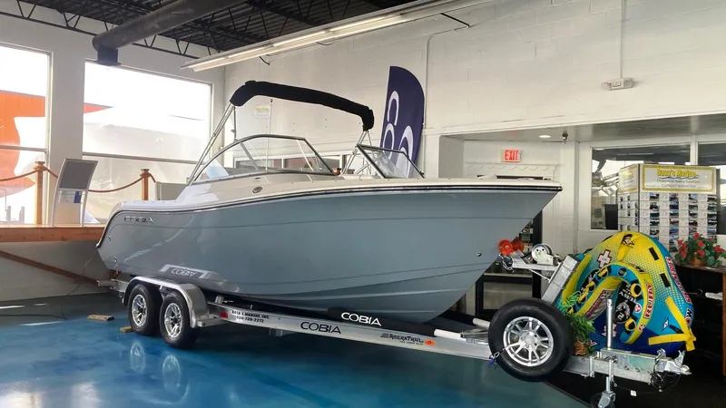 Slide: The Image of 2022 Cobia 220 Dual Console boat on trailer in showroom. - 1