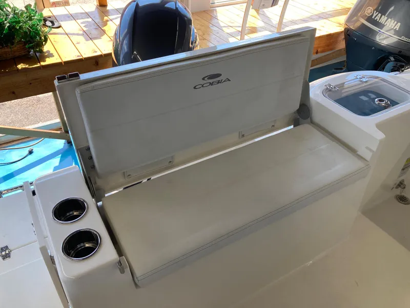 Slide: The Image of 2022 Cobia 220 Dual Console boat with open storage compartment and cup holders. - 6