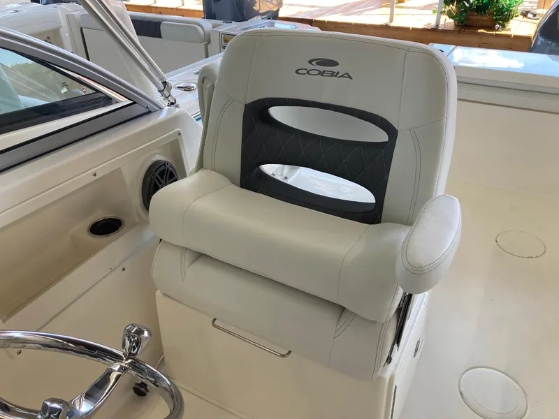 Slide: The Image of 2022 Cobia 220 Dual Console boat captain's chair with logo, white and black upholstery. - 8