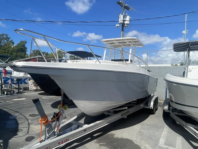 Slide: The Image of 2022 Wellcraft 275cc boat on trailer in marina under blue sky. - 2