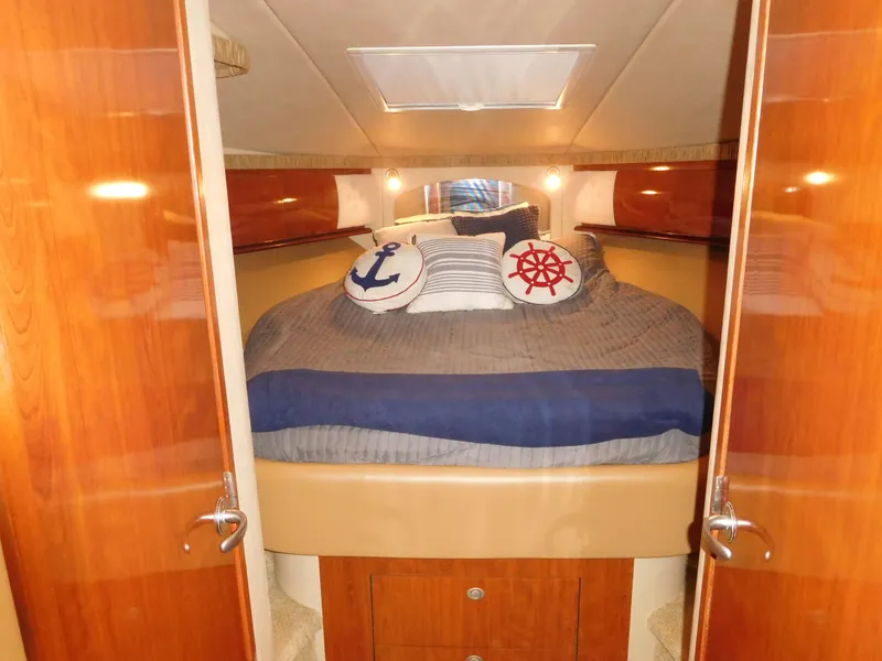 Slide: The Image of 2005 Sea Ray 420 Sundancer cabin with cozy bed and nautical-themed pillows. - 41