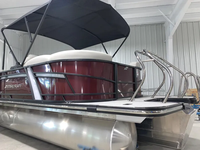 Slide: The Image of 2024 Starcraft SLS 3 pontoon boat with canopy in a showroom. - 2