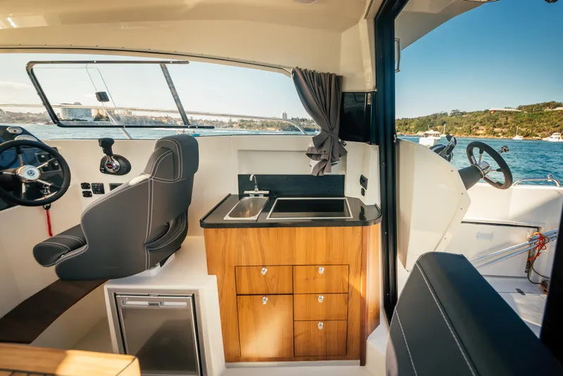 Slide: The Image of 2022 Parker Poland 800 Weekend boat interior with steering wheel, kitchenette, and scenic water view. - 18