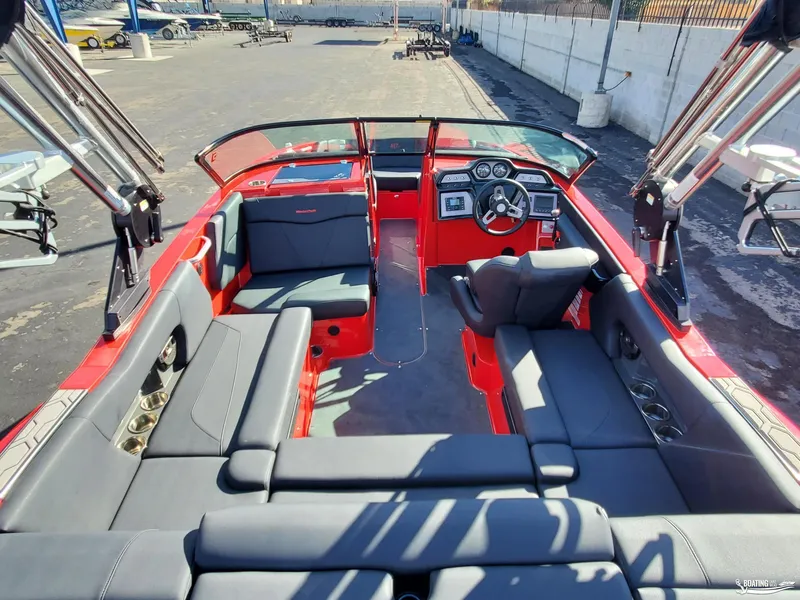 Slide: The Image of 2020 MasterCraft NXT20 boat interior with red and gray seating, dashboard, and cup holders. - 11