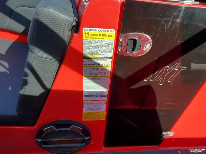 Slide: The Image of 2020 MasterCraft NXT20 boat interior with capacity label, red and black design. - 15