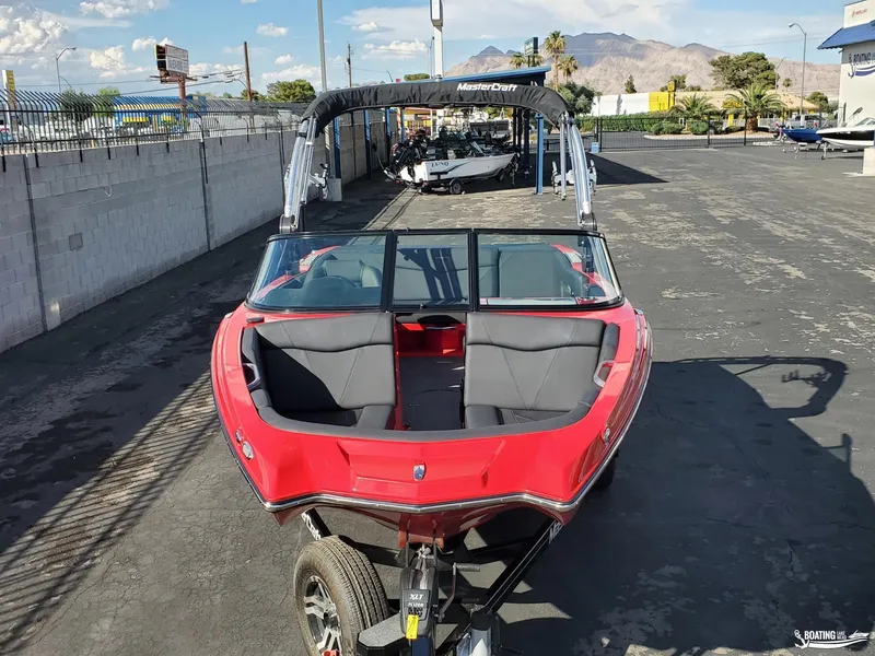 Slide: The Image of 2020 MasterCraft NXT20 boat, red exterior, parked on a trailer in a dealership lot. - 3