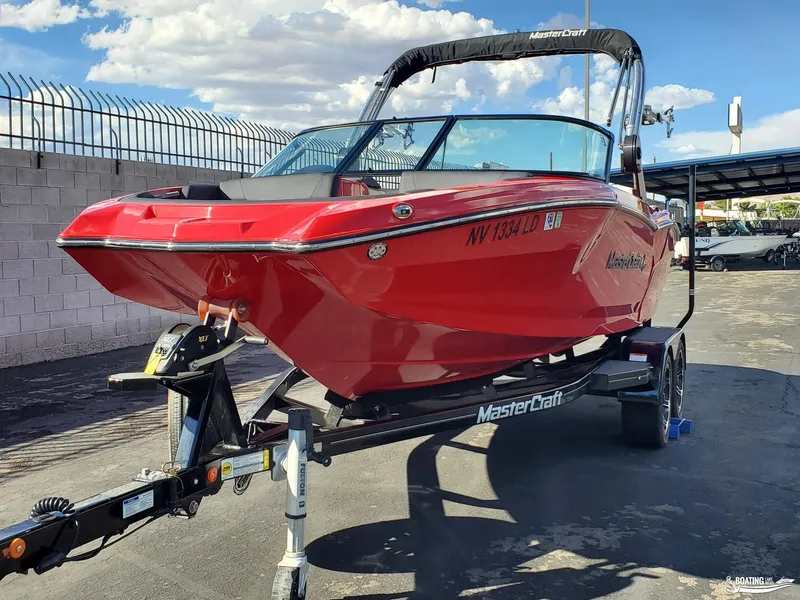 Slide: The Image of Red 2020 MasterCraft NXT20 boat on trailer, parked outdoors under blue sky. - 4