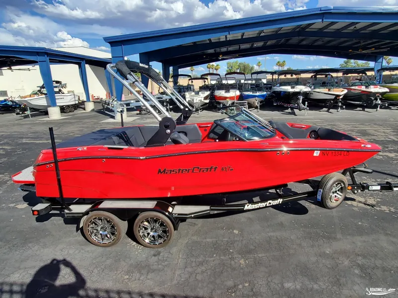 Slide: The Image of Red 2020 MasterCraft NXT20 boat on trailer at dealership under blue canopy. - 6