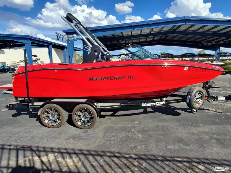 Slide: The Image of Red 2020 MasterCraft NXT20 boat on trailer under blue sky. - 7