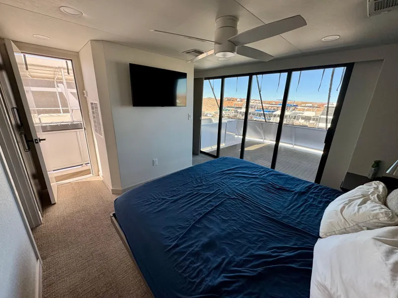 Slide: The Image of Modern bedroom with large windows, blue bedding, and wall-mounted TV in Adonia Obsession Share Trip #9. - 24