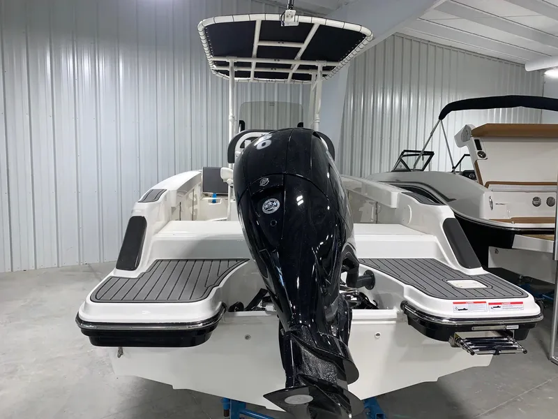 Slide: The Image of 2024 Bayliner Trophy 20CC boat in a showroom, rear view with outboard motor. - 2
