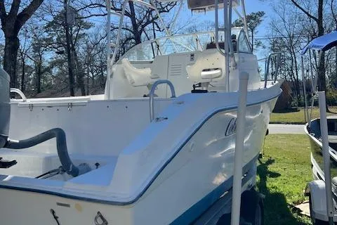 Slide: The Image of 2000 Cobia 240 Walk-Around boat on grass, showcasing deck and seating area. - 22