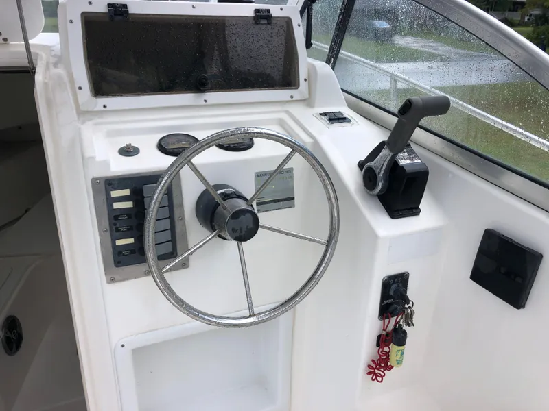 Slide: The Image of 2000 Cobia 240 Walk-Around boat helm with steering wheel and controls. - 7