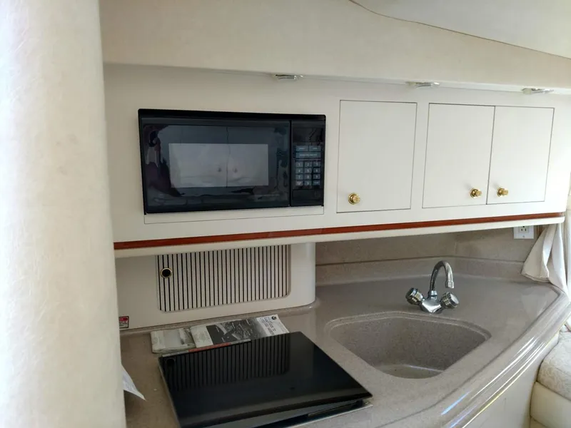 Slide: The Image of 2001 Sea Ray 290 Amberjack kitchen with microwave, sink, and storage cabinets. - 10