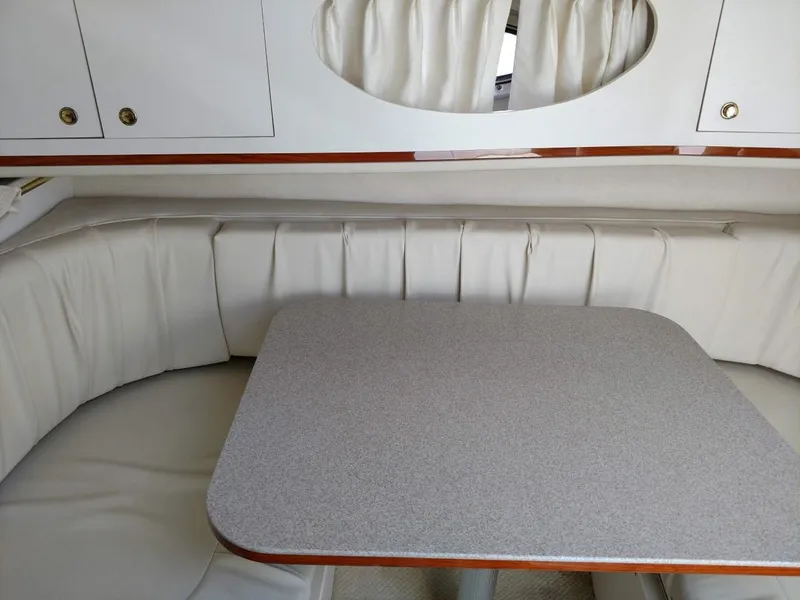 Slide: The Image of 2001 Sea Ray 290 Amberjack cabin interior with cushioned seating and table. - 12