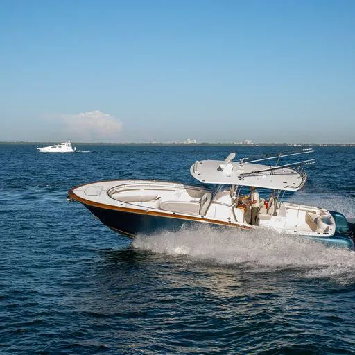 Slide: The Image of 2019 Mag Bay Center Console boat cruising on open water under clear blue sky. - 2