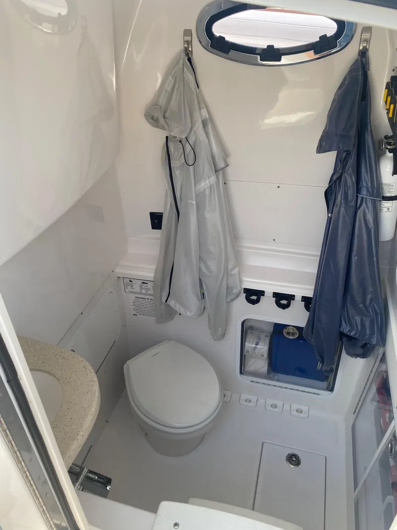 Slide: The Image of 2019 Mag Bay Center Console boat interior with toilet and hanging raincoats. - 6