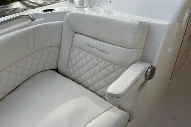 Slide: The Image of 2024 Grady-White Freedom 307 boat seat with quilted white upholstery and armrest. - 21