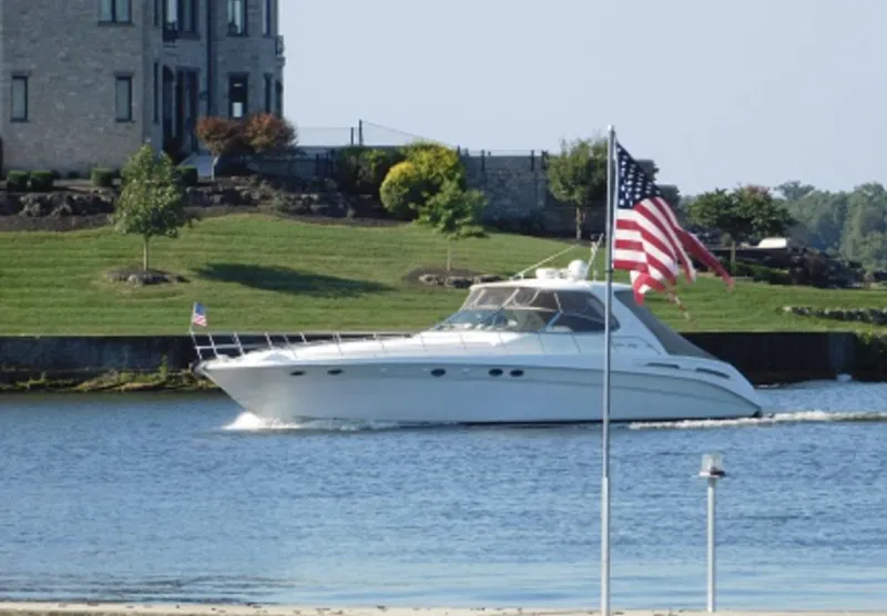 Slide: The Image of 2000 Sea Ray 540 Sundancer cruising on a scenic river with American flags. - 4