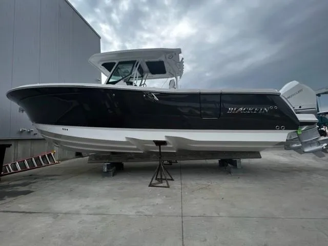 Slide: The Image of 2023 Blackfin 302 CC boat on a concrete surface under a cloudy sky. - 1