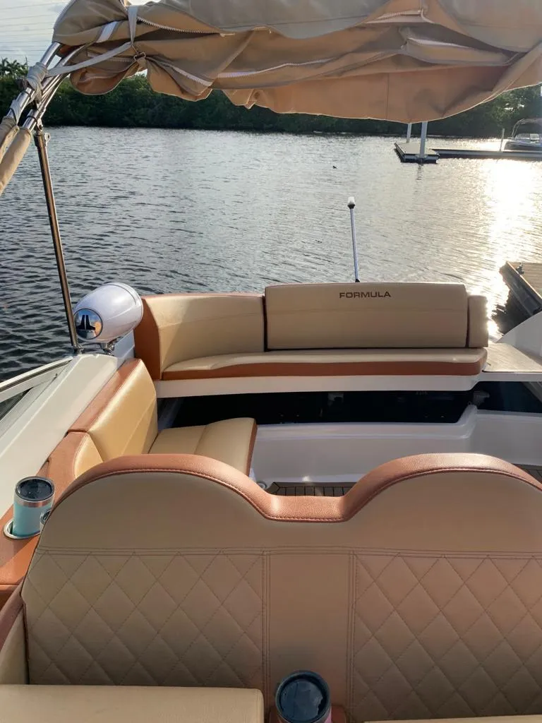 Slide: The Image of 1999 Formula 280 Bowrider boat with tan leather seats and canopy on a calm lake. - 13