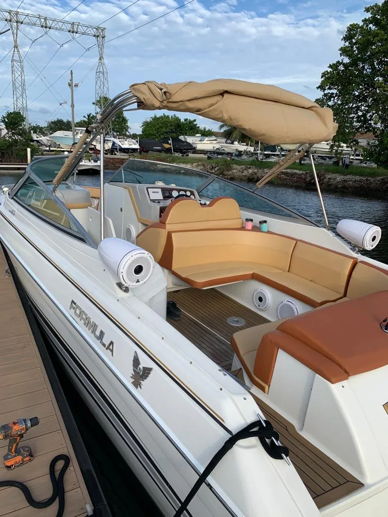 Slide: The Image of 1999 Formula 280 Bowrider boat docked, featuring spacious seating and a beige canopy. - 20