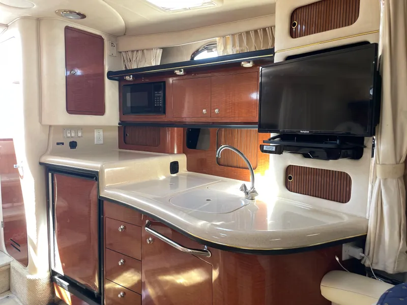 Slide: The Image of 2002 Sea Ray 340 Sundancer galley with sink, microwave, and TV. - 11