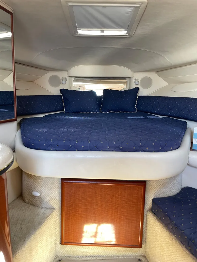 Slide: The Image of 2002 Sea Ray 340 Sundancer cabin interior with blue bedding and wooden accents. - 13