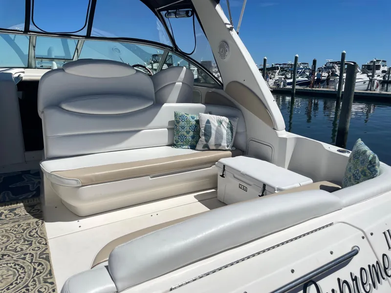 Slide: The Image of 2002 Sea Ray 340 Sundancer boat interior with white seating and decorative pillows at a marina. - 2