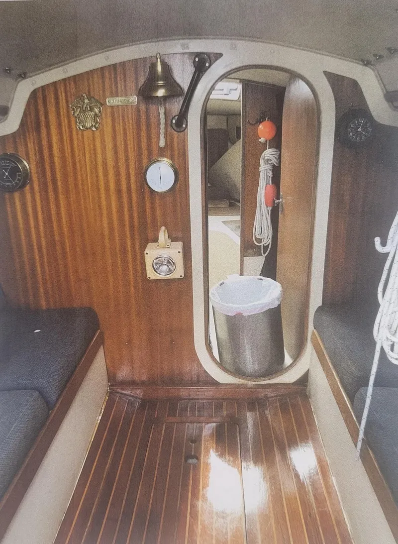 Slide: The Image of Interior of a 1980 J Boats J30 sailboat, featuring wood paneling and nautical decor. - 7