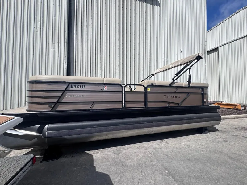 Slide: The Image of 2022 Sweetwater SW 2286 C pontoon boat parked outside a warehouse. - 1