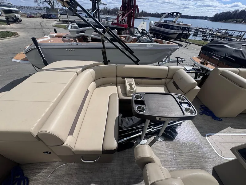 Slide: The Image of 2022 Sweetwater SW 2286 C pontoon boat with beige seating and table, docked by a lake. - 11