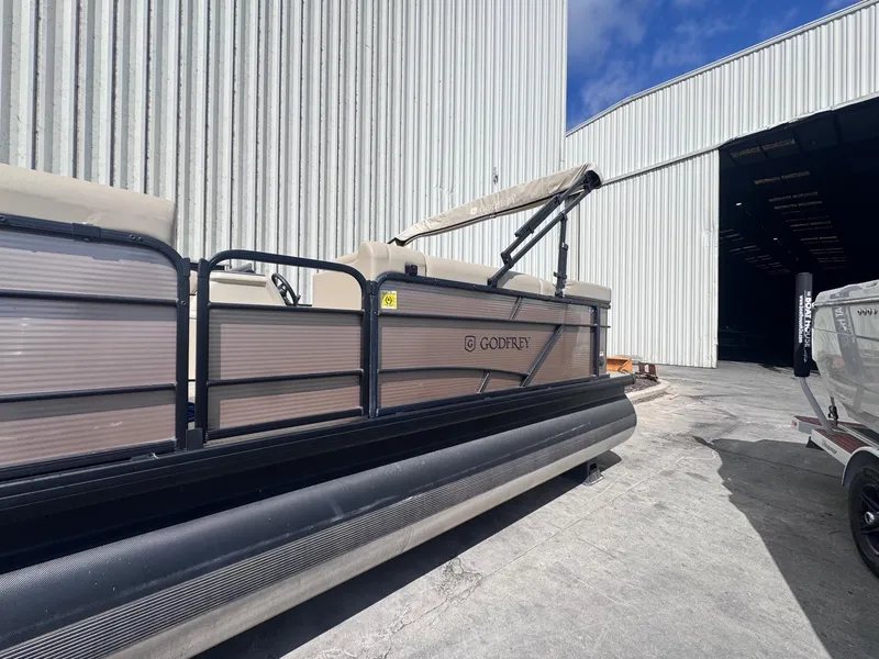 Slide: The Image of 2022 Sweetwater SW 2286 C pontoon boat parked outside a large warehouse. - 2