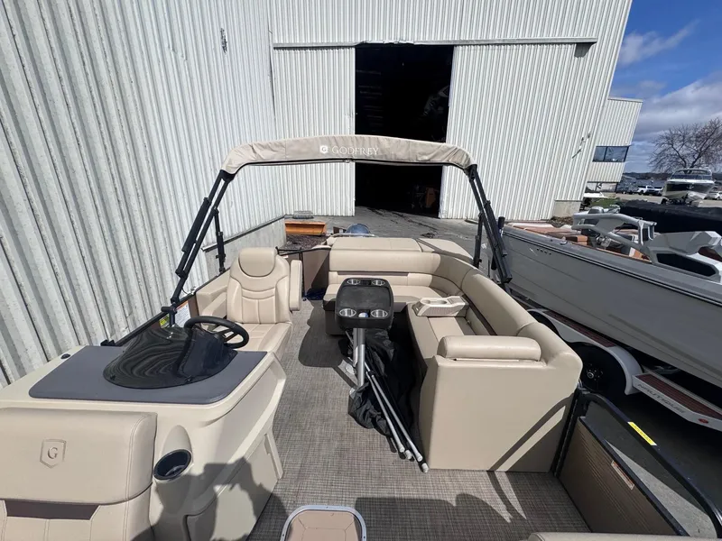 Slide: The Image of 2022 Sweetwater SW 2286 C pontoon boat with beige seating, docked near a warehouse. - 7