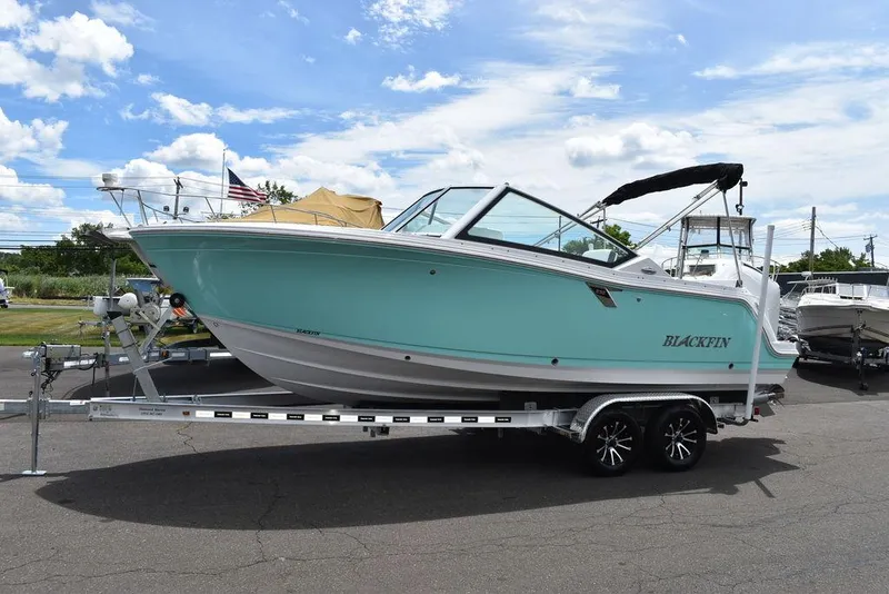 Slide: The Image of 2023 Blackfin 232 DC boat on a trailer under a blue sky. - 12