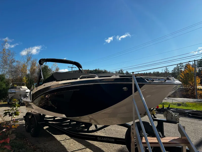 Slide: The Image of 2023 Glastron GTD 245 boat on trailer under clear blue sky. - 2