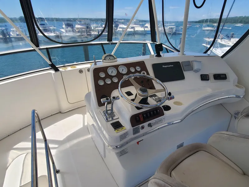 Slide: The Image of 2003 Silverton 38 Convertible yacht helm with steering wheel and control panel, docked at marina. - 12