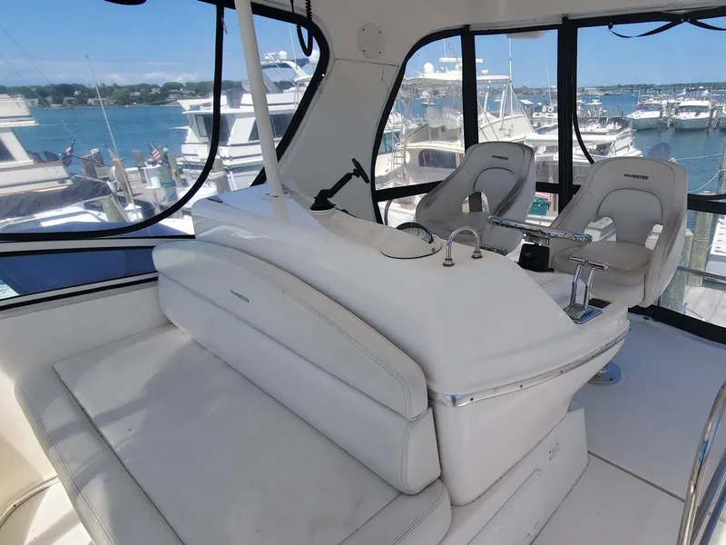 Slide: The Image of 2003 Silverton 38 Convertible yacht interior with helm and seating, overlooking marina. - 13