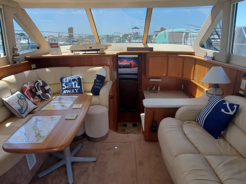 Slide: The Image of 2003 Silverton 38 Convertible yacht interior with beige seating, nautical decor, and a wooden table. - 15